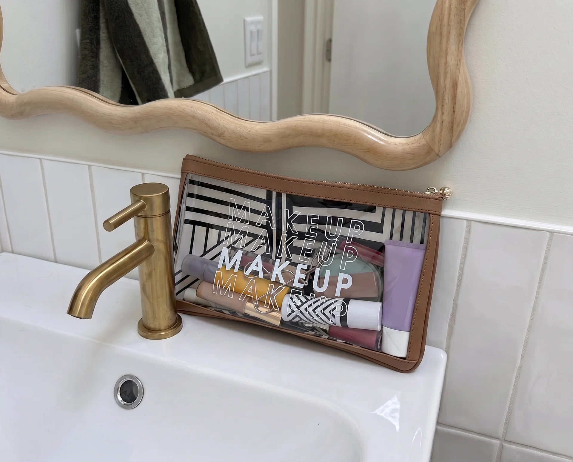 Clear MAKEUP bag organizer filled with makeup, styled on a bathroom vanity