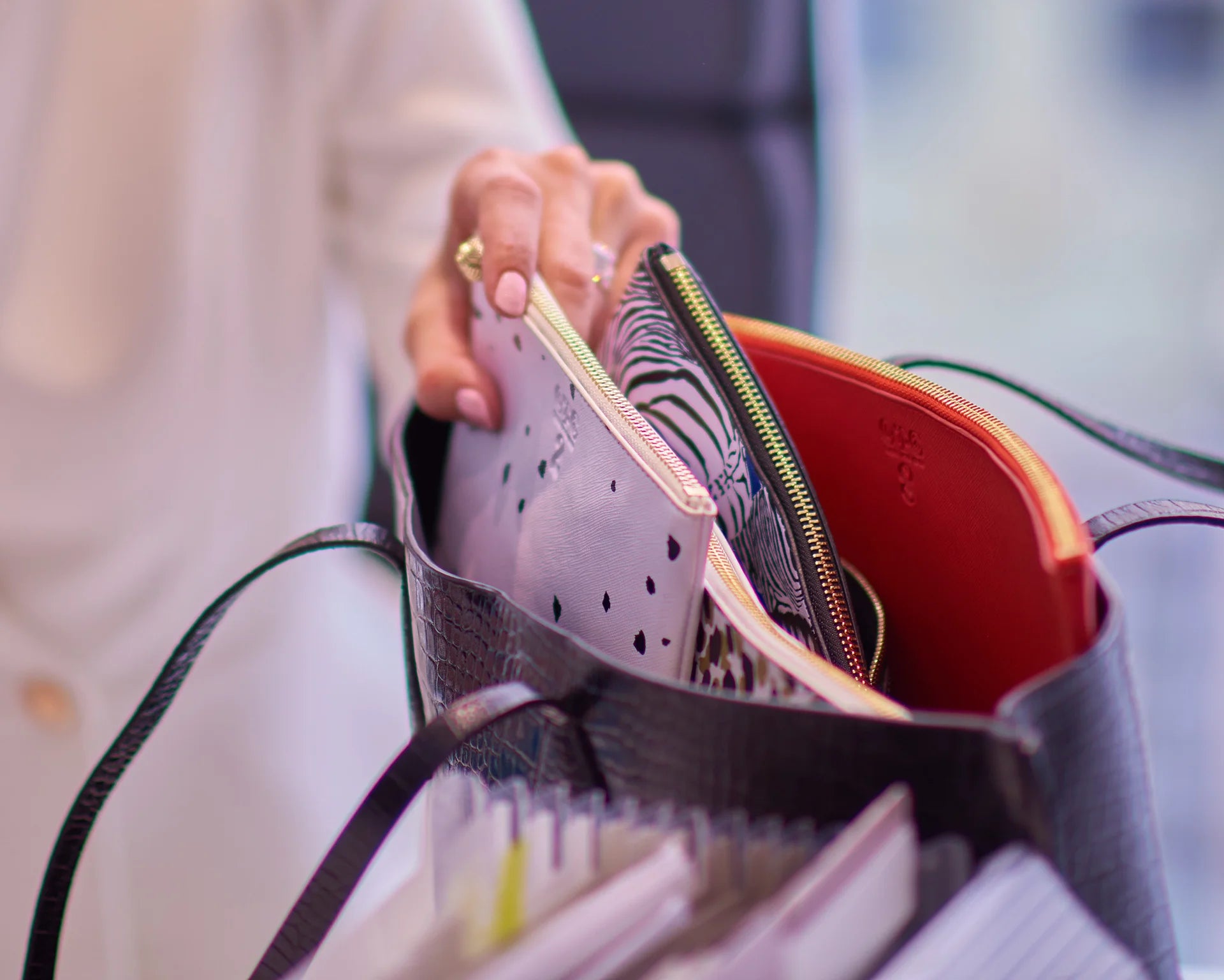Hand lifting an OTG clear-window organizer pouch out of a tote bag